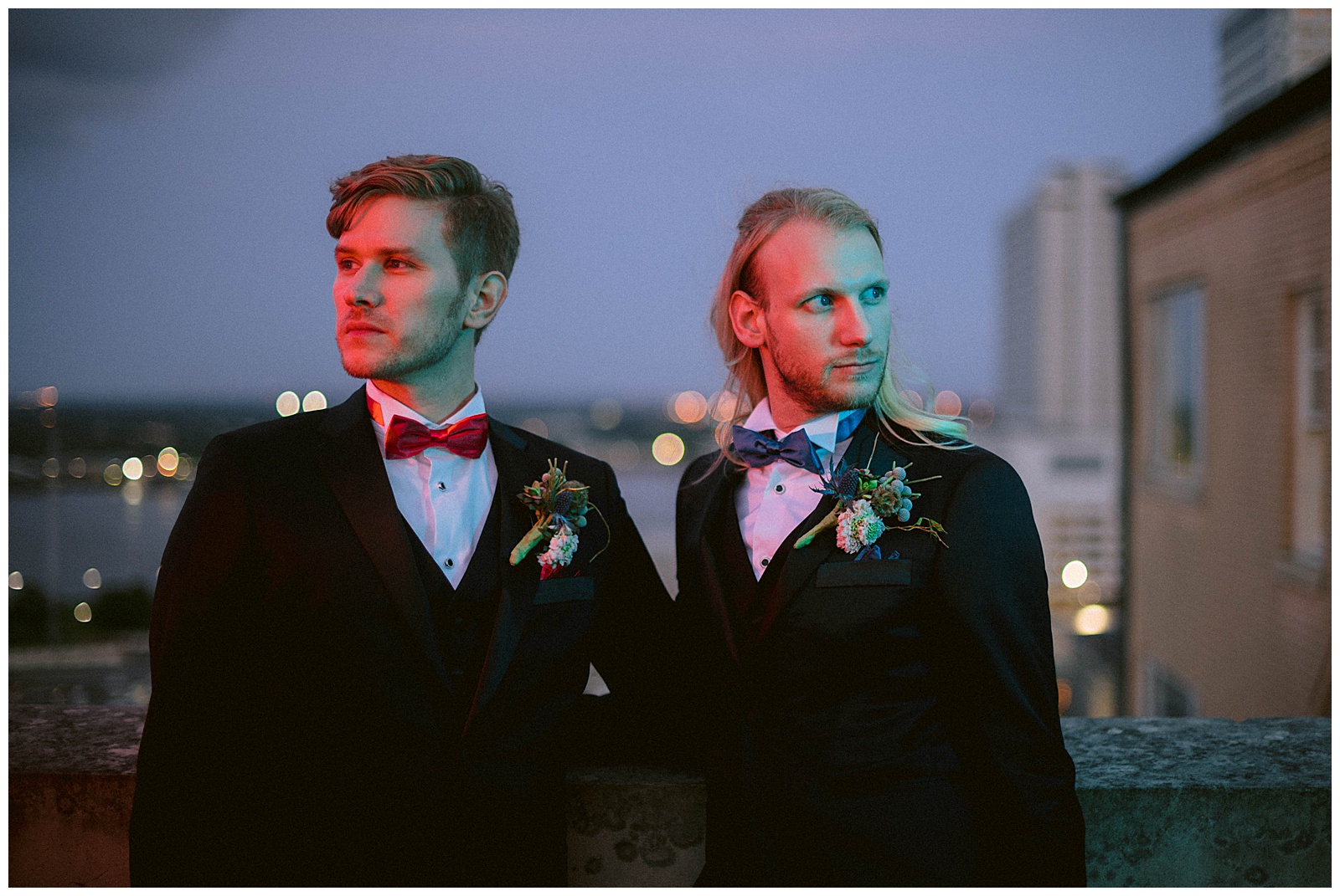 Two grooms pose in the neon light of Hotel Monteleone