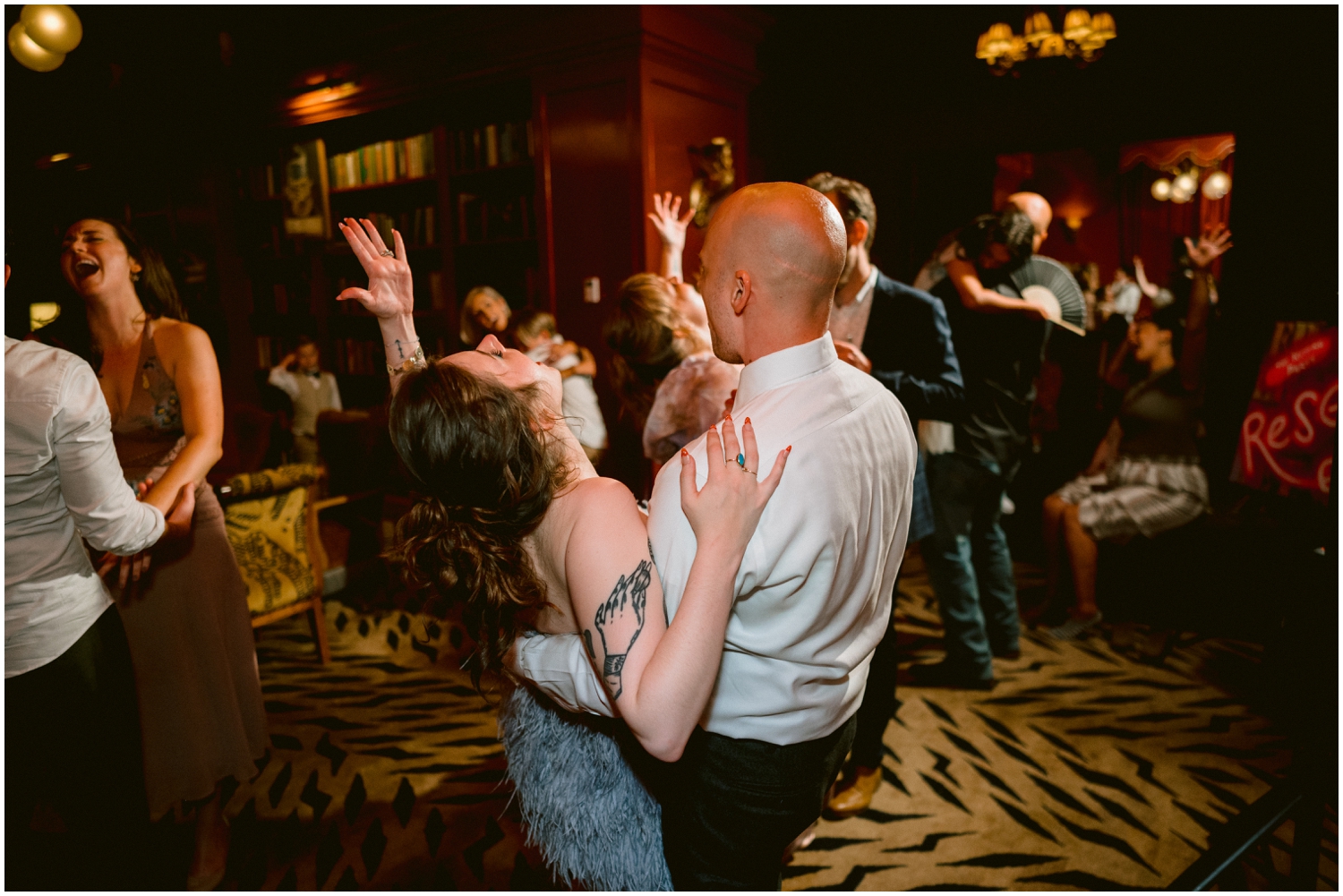 The bride and groom throw their hands up while they dance.