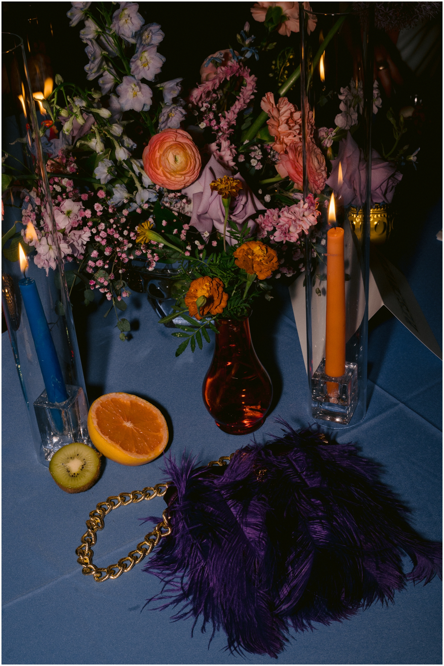 A blue handbag sits beside a floral arrangement lit by direct flash wedding photography.