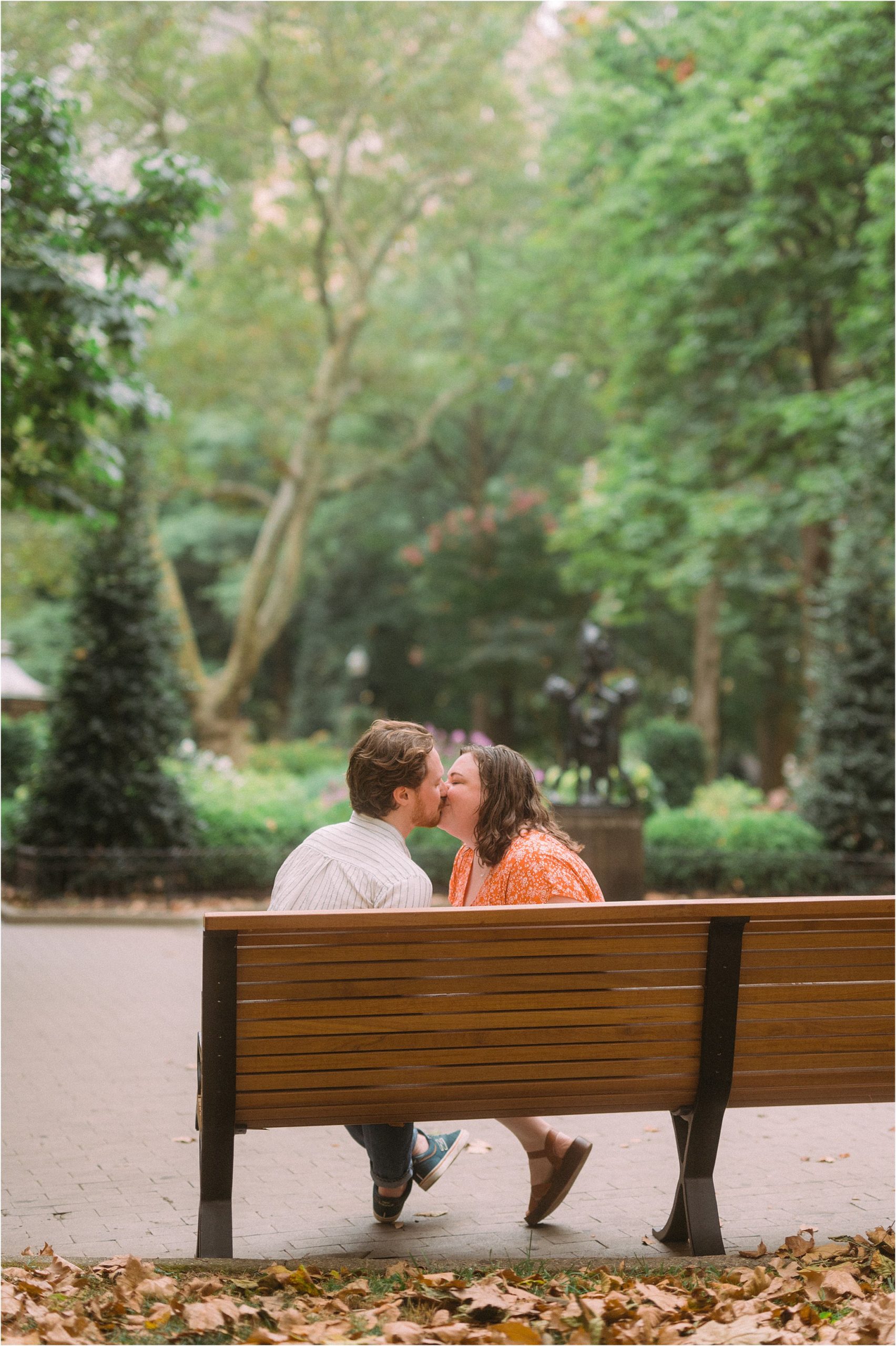 A couple kisses on a park bench for their Philadelphia engagement photos in Rittenhouse Square.