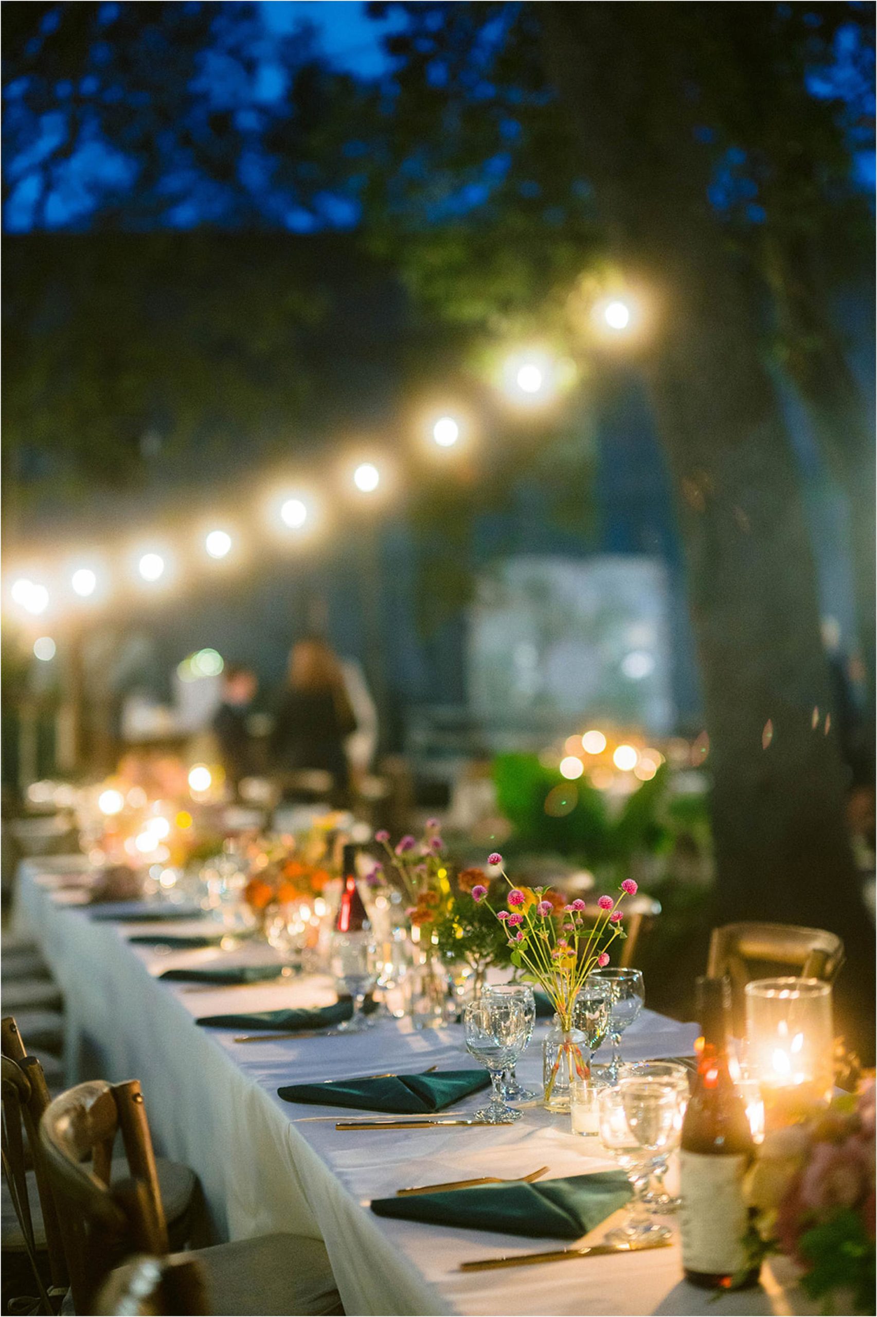 A reception table is set for a candlelit wedding in a courtyard wedding venue.