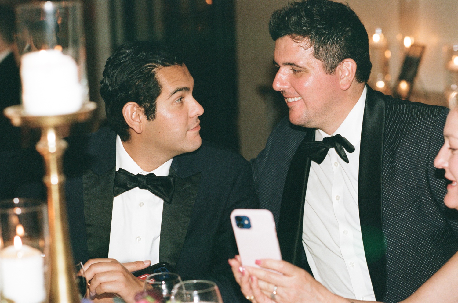 Two men in tuxes sit talking at a Philadelphia wedding reception.