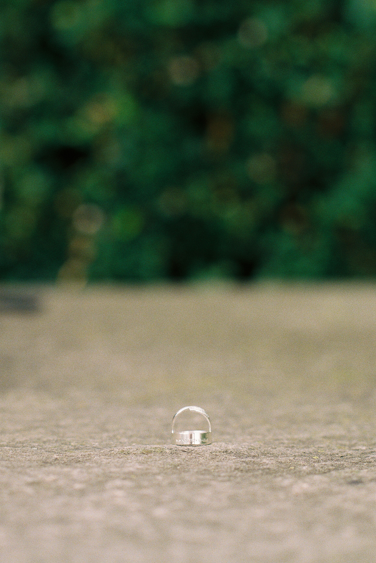 Wedding rings sit on a park walkway.