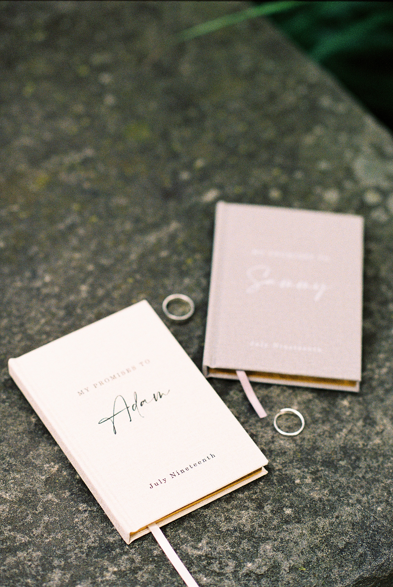 Vow books and wedding rings sit on a park sidewalk at a Philadelphia elopement.