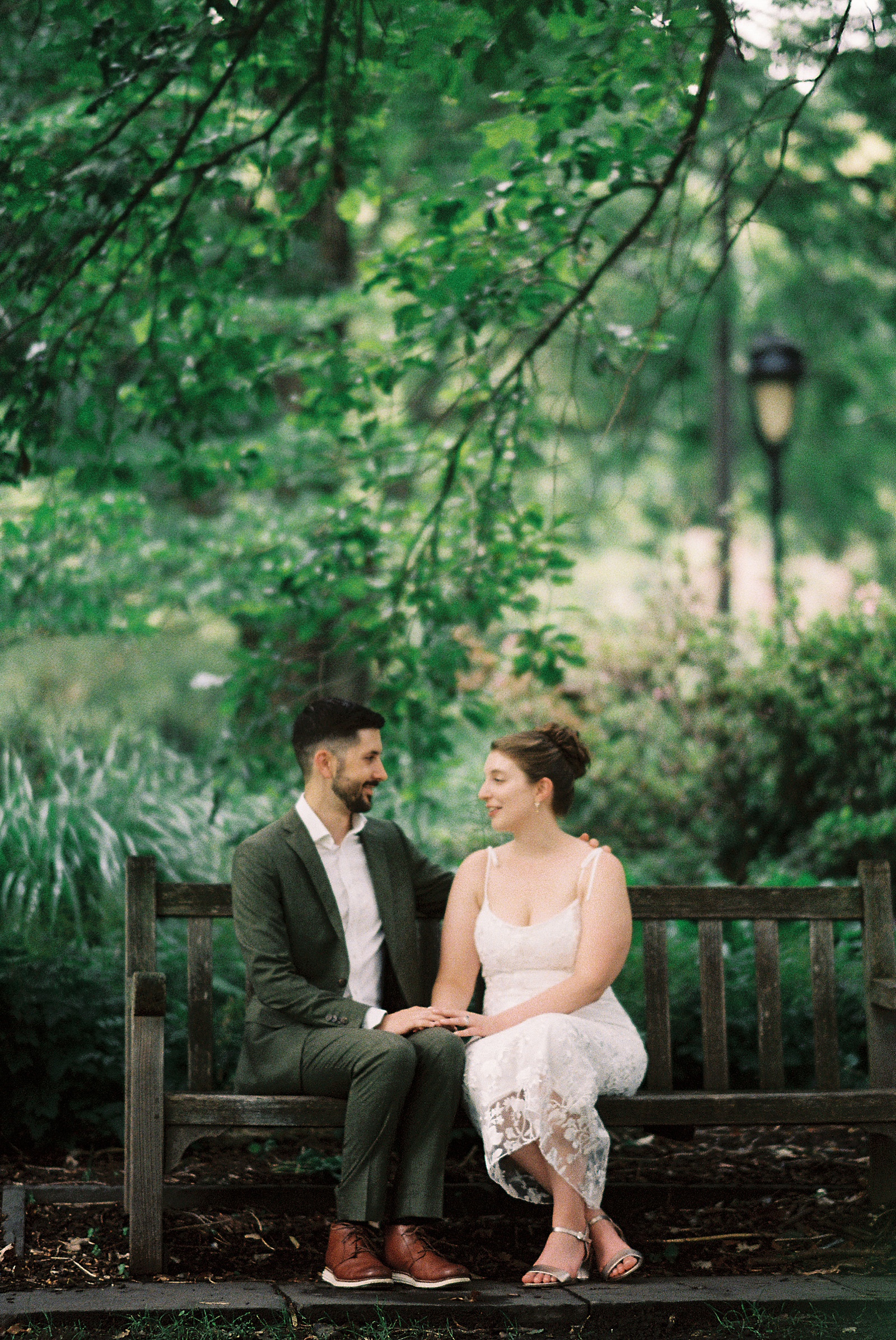 A bride and groom sit on a park bench after their Philadelphia elopement.