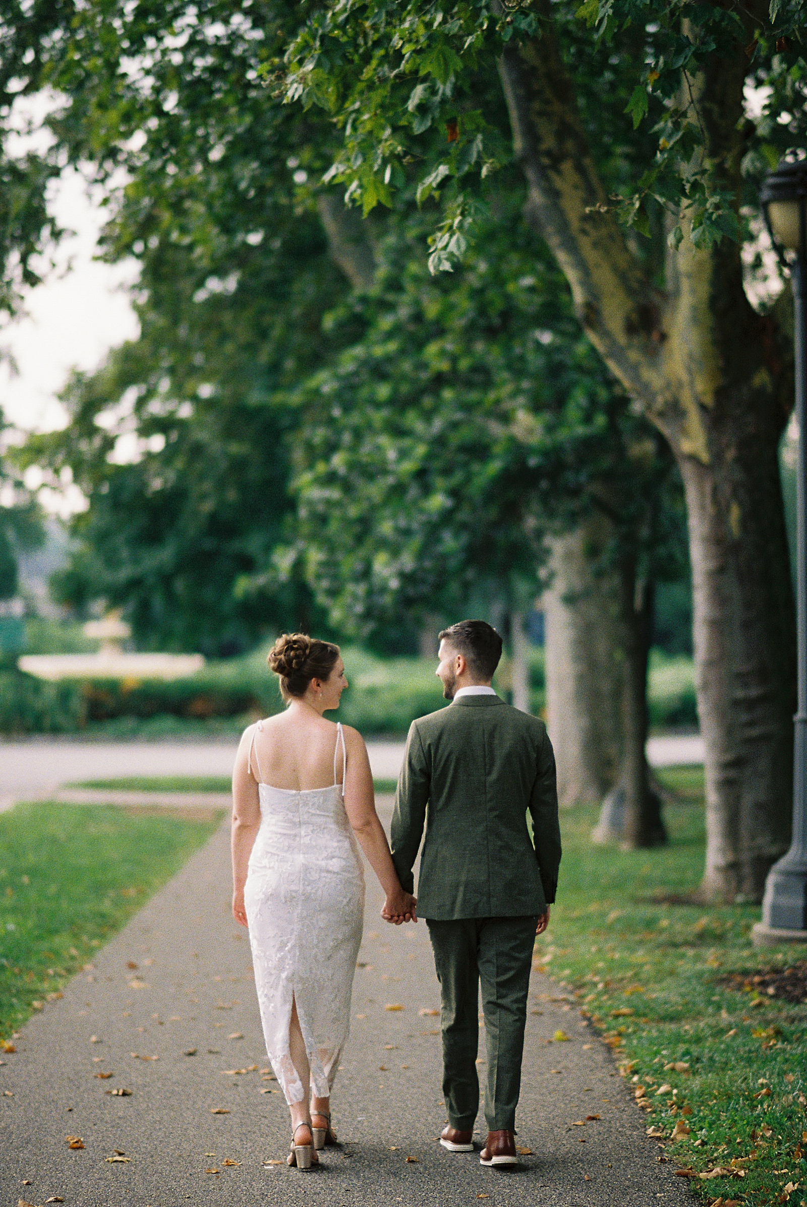A bride and groom hold hands walking away from a Philadelphia wedding photographer.
