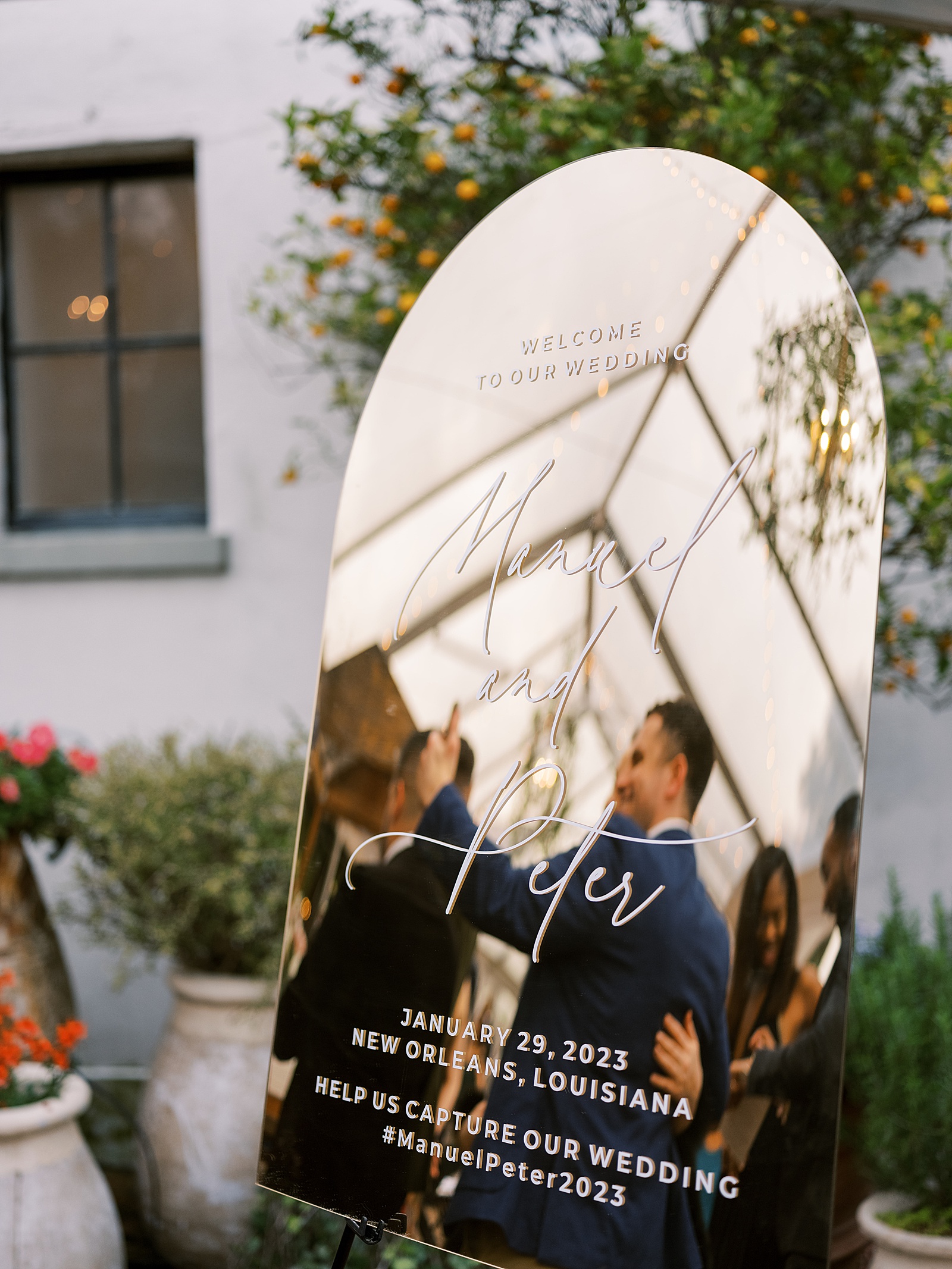 A mirror sign reflects wedding guests gathering in the courtyard of Il Mercato.