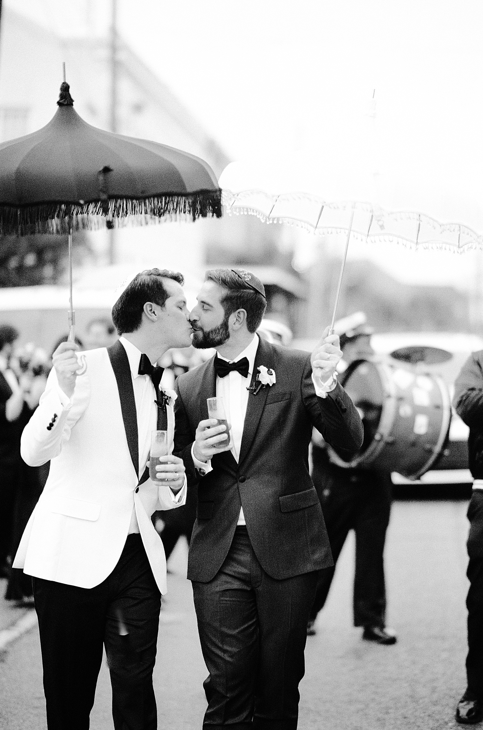 Two grooms kiss during a New Orleans wedding parade.
