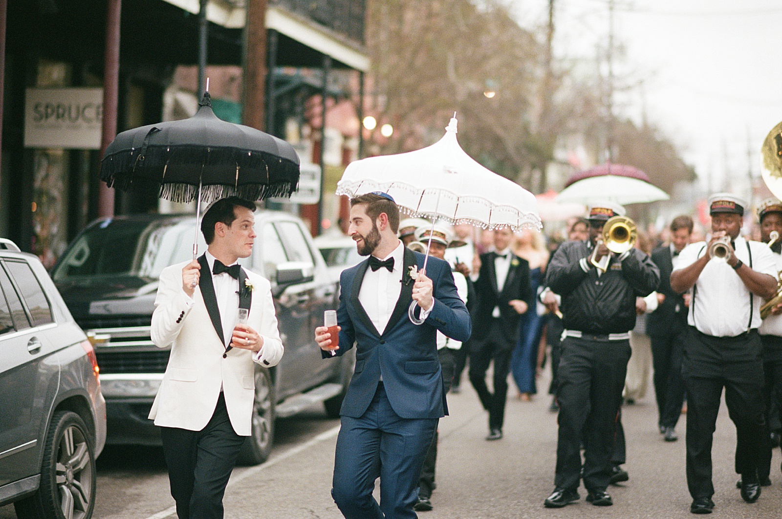 Two grooms lead a New Orleans wedding parade in wedding portraits on film photography.