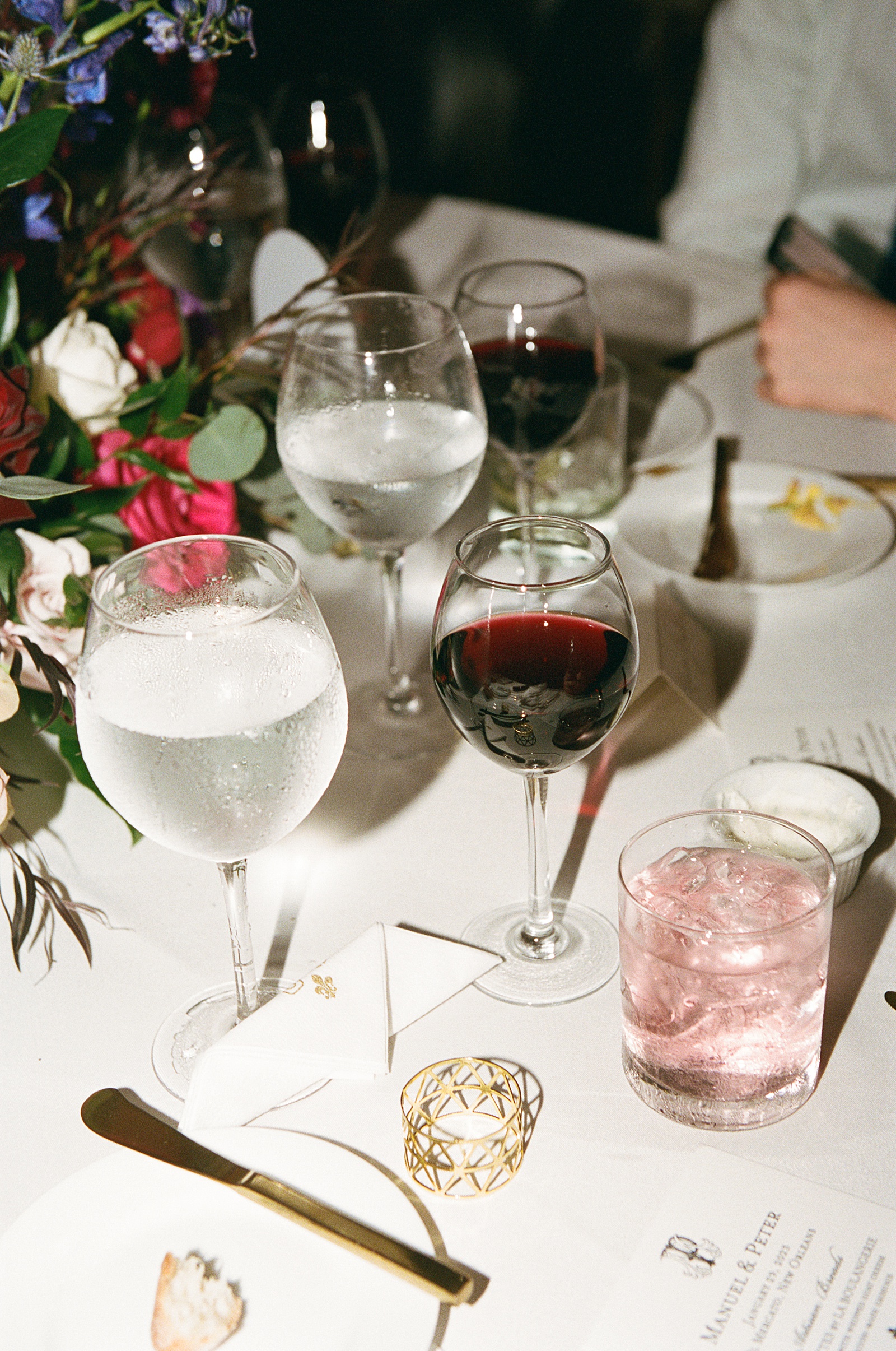 A pink cocktail sits beside a glass of red wine in a photo using direct flash photography.
