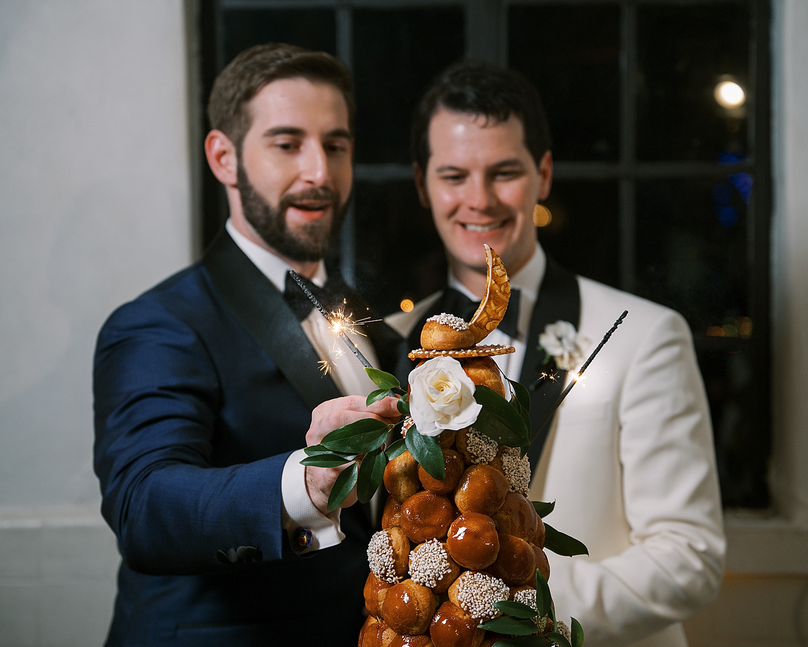 Two grooms put sparklers on a wedding croquembouche.