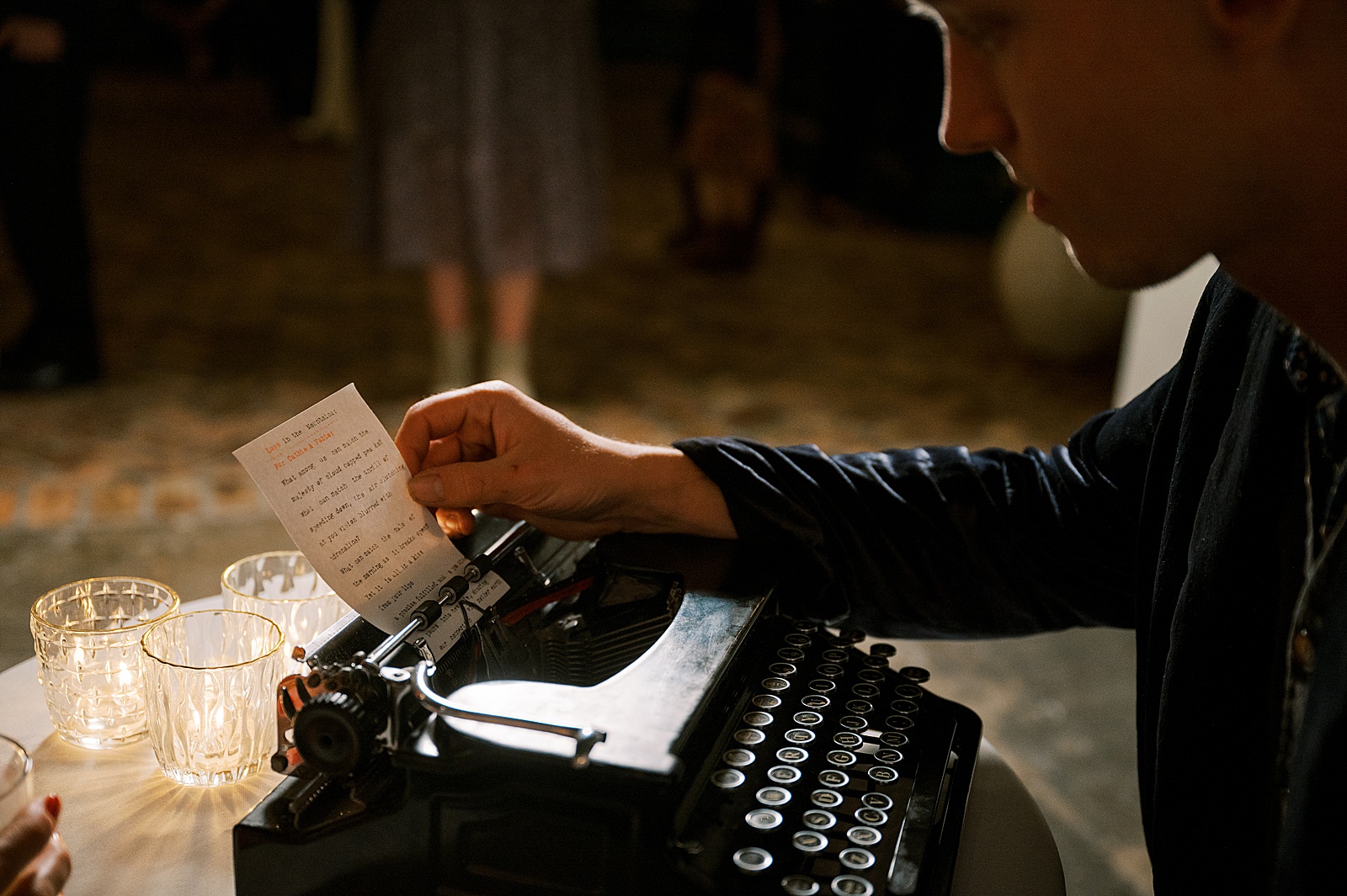 A wedding poet pulls a piece of paper off a typewriter in a creative wedding photo.