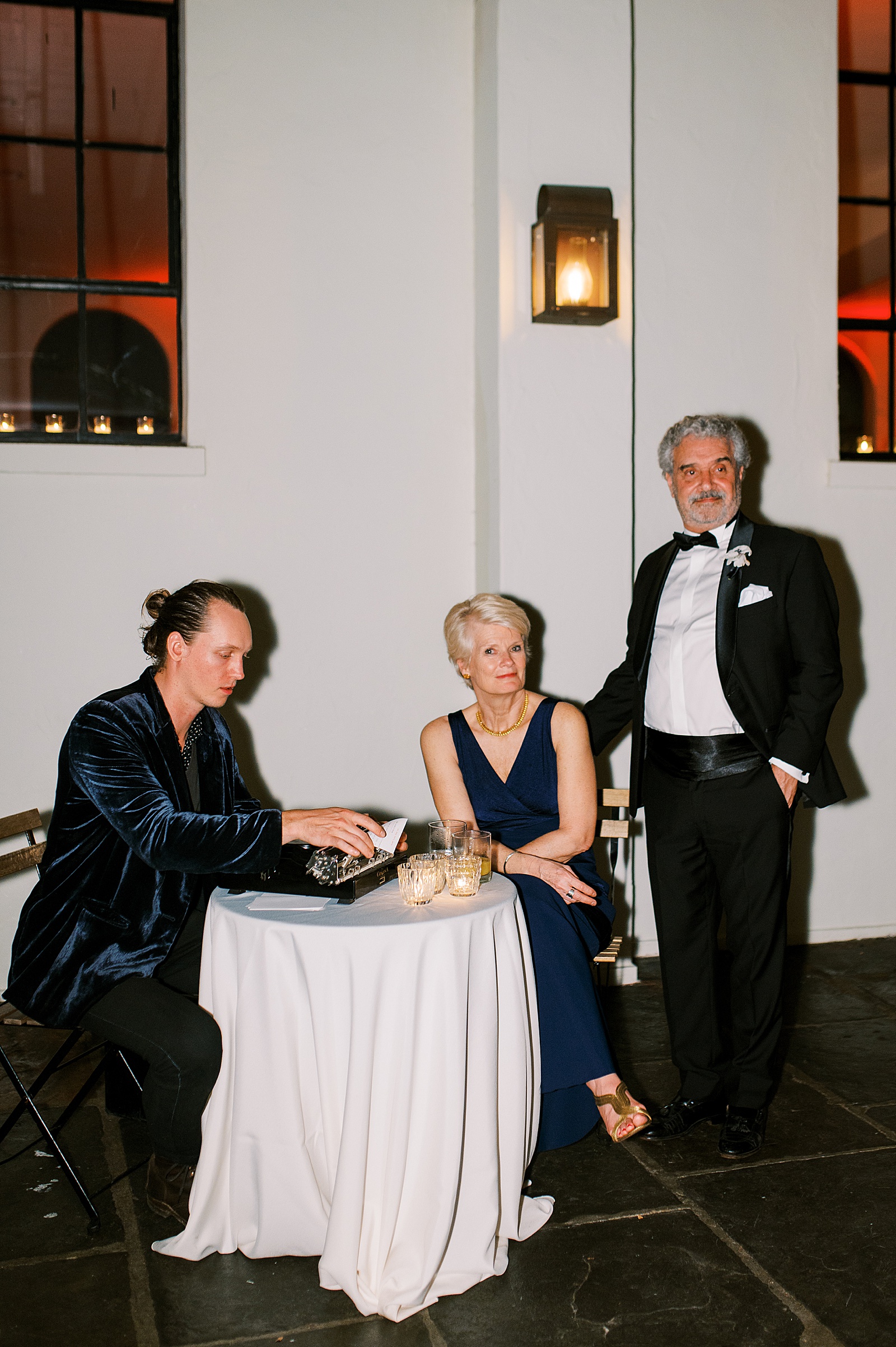 Two guests sit with a wedding poet in direct flash wedding photography.