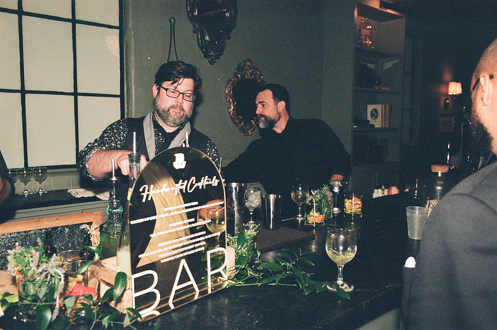Bar tenders mix signature wedding cocktails in wedding photography on film.