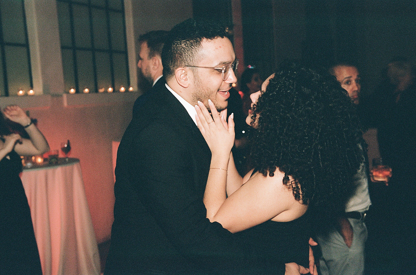 Two wedding guests dance closely in a film photo.