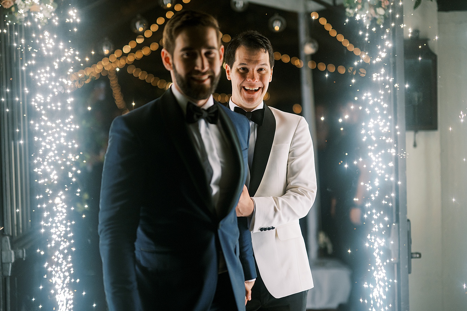 Two grooms walk between sparkler machines for their wedding exit on film photography.