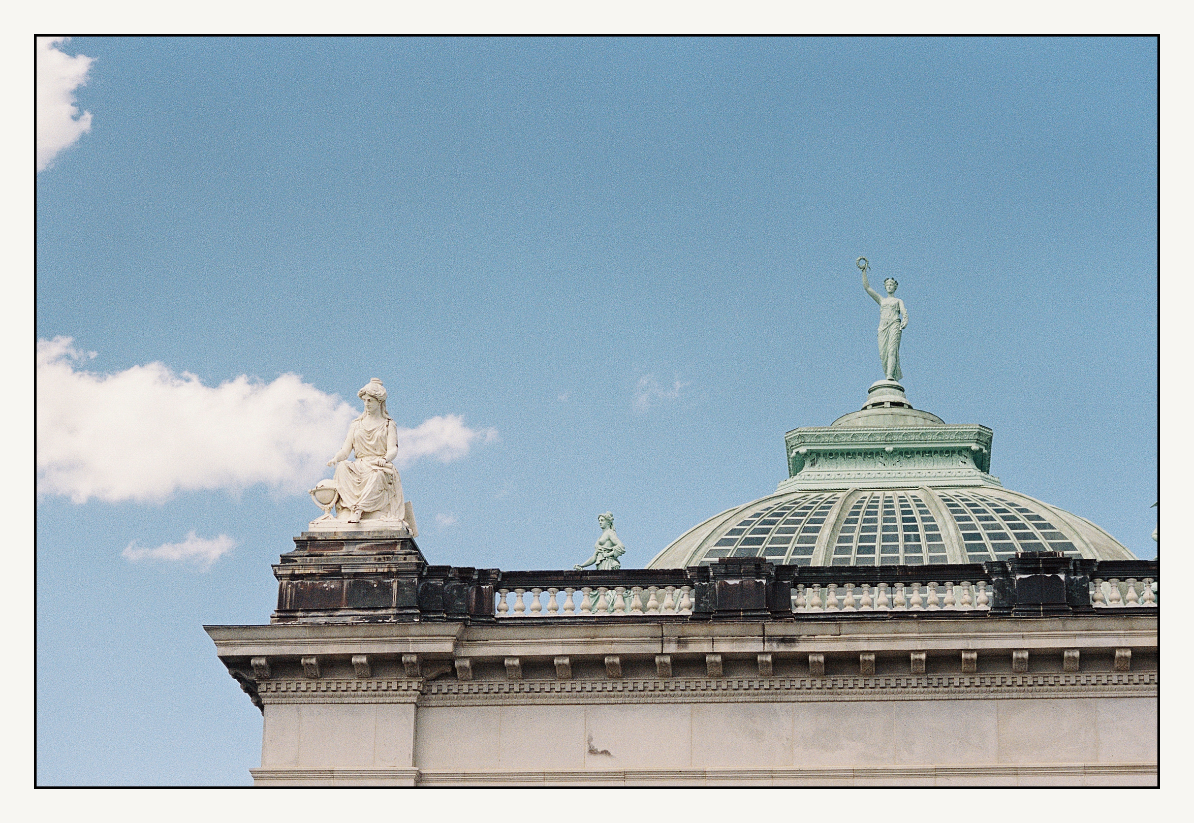 Statues sit atop the Please Touch Museum on a sunny day.