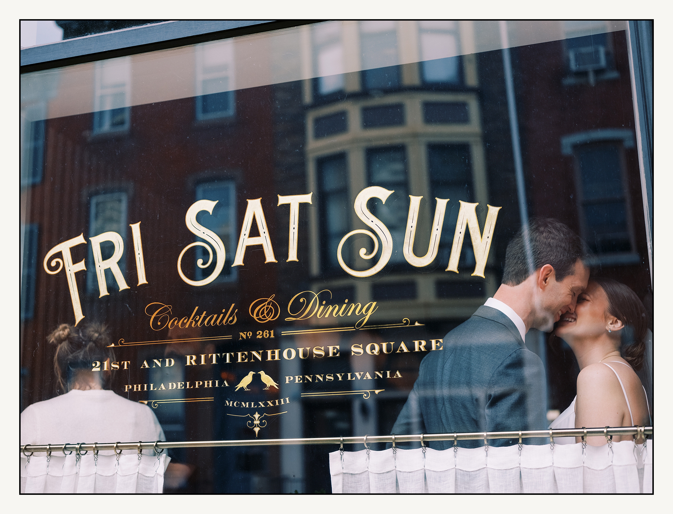 A bride and groom kiss inside a Rittenhouse Square restaurant before their Reading Terminal Market wedding.