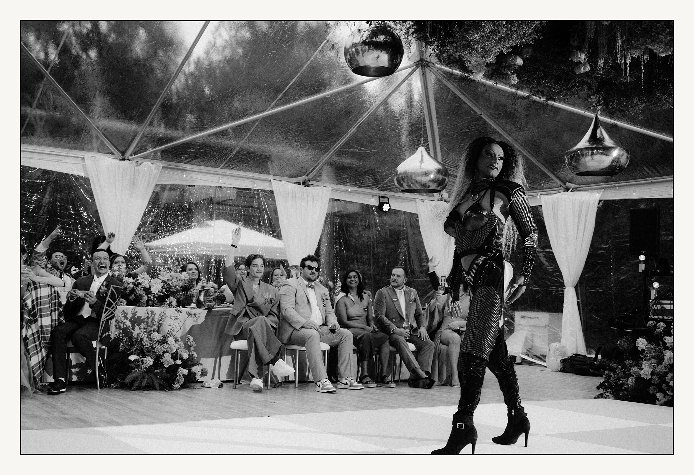 Wedding guests watch a drag queen perform at a reception.
